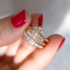 a woman's hand holding a gold ring with three baguettes on it