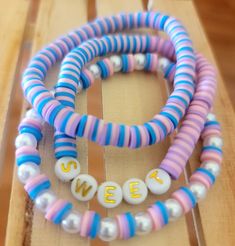 two bracelets with letters on them sitting on top of a wooden table