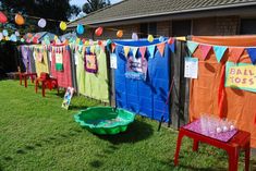 there are many colorful clothes hanging on the line in front of a house with an empty green bowl