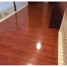 an empty room with hard wood flooring and white railings on the side walk