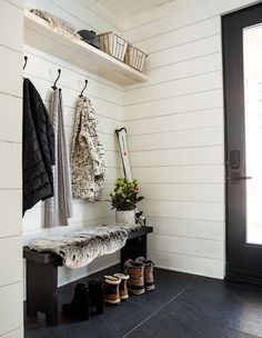 there is a bench and coat rack in the entryway with shoes on it next to a door