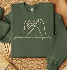 a green sweatshirt with the words paradise keeper on it and two hands holding each other