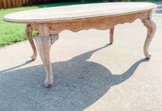 an old wooden table sitting in the middle of a driveway next to a fence and grass