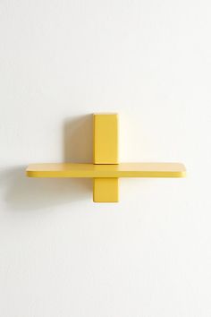 a yellow shelf on the wall with a white background