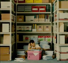 a woman is sitting on the floor in front of a box with files and folders