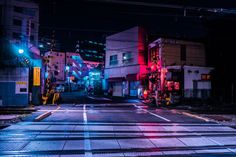 an empty city street at night with buildings lit up in red, white and blue