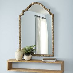 a mirror sitting on top of a wooden table next to a vase and book shelf