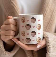 a woman is holding a coffee mug with hearts on it and the face of a baby