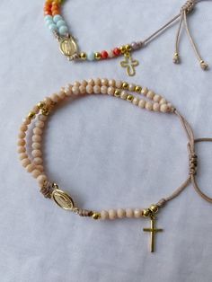 three bracelets with cross charms and beads on white cloth background, closeup shot