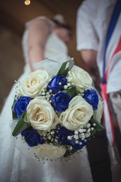 a bride holding a bouquet of white and blue flowers