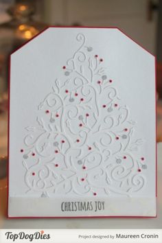 a white christmas tree card with red trimmings on the front and bottom, sitting on a table