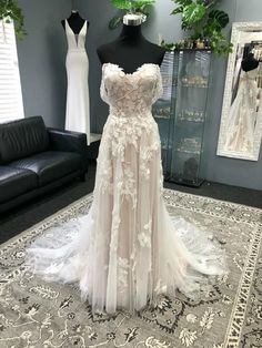 a wedding dress on display in a room with mannequins and other dresses