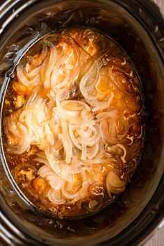 the food is being cooked in the crockpot with noodles and broth on top