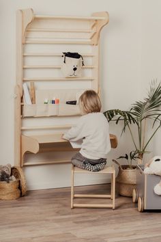 a little boy sitting on top of a wooden chair in front of a computer desk