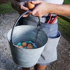 a person holding a bucket with eggs in it and an orange wire sticking out of the top