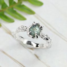 a white gold ring with a green diamond in the center and diamonds on each side