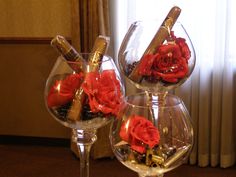 two wine goblets with red roses in them