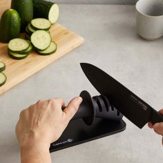 a person using a knife to cut cucumbers on a cutting board with a knife