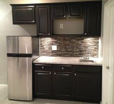 a kitchen with black cabinets and silver appliances