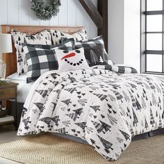 a bed covered in black and white plaid comforter with snowman on the pillow