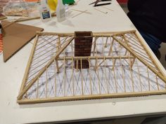 a model house made out of wood sitting on top of a white table next to other items