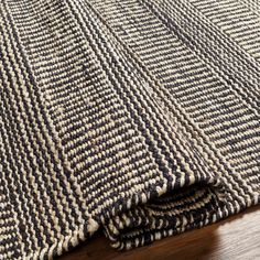 a close up of a rug on a wooden floor with wood floors and furniture in the background