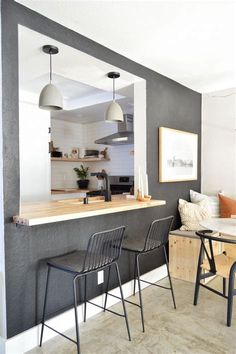 a kitchen and dining area with chairs, table, counter and pictures on the wall