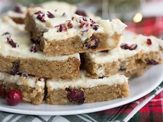 a white plate topped with pieces of cake next to a pile of cranberries