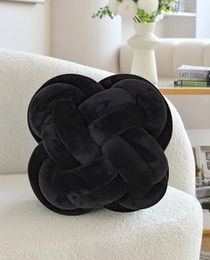 a black pillow sitting on top of a white chair