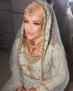 a woman wearing a veil and headpiece sitting in front of a dresser with drawers