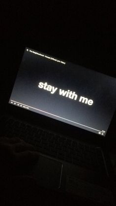 an open laptop computer sitting on top of a dark table with the words stay with me written on it