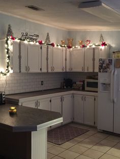 a kitchen with white cabinets and christmas lights