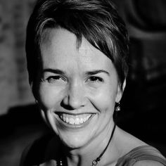 a black and white photo of a woman with short hair smiling at the camera,