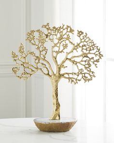 a gold tree sculpture sitting on top of a white table