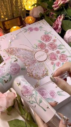 a woman is opening a pink box with flowers on it and the inside of it