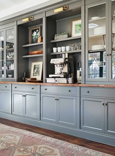 a kitchen with gray cabinets and an area rug in front of the counter top that has pictures on it