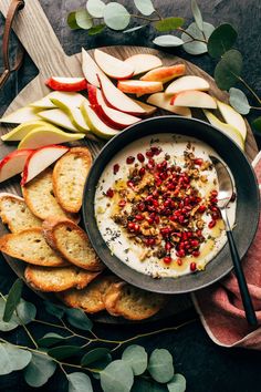 a bowl of yogurt surrounded by sliced apples and crackers