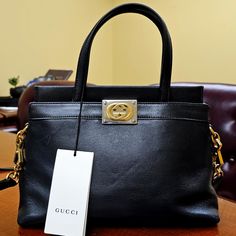 Authentic And Genuine Gucci Product - Rfid Chip This Item Is An Open Box And Missing The Dust Bag. Crafted From Black Lamb Leather With Gold- And Silver-Toned Hardware, This Bag Boasts A Viscose Lining And An Interlocking G Plaque. The Interior Offers Two Open Compartments. It Features Double Top Handles With A Drop Of Approximately 4.25", And A Detachable, Adjustable Shoulder Strap With A Drop Ranging From Approximately 18.5". The Bag's Dimensions Are Approximately 11" In Width, 8.5" In Height, Elegant Business Bags With Logo Plaque, Elegant Formal Bag With Logo Plaque, Formal Gucci Bags With Logo Plaque, Elegant Gucci Bag With Gold-tone Logo Plaque, Black Workwear Bag With Horsebit Detail, Black Horsebit Detail Bag For Work, Designer Black Bag With Horsebit Detail, Designer Black Bags With Horsebit Detail, Black Designer Bag With Horsebit Detail