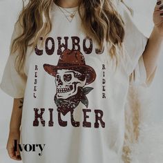 Elevate your country style with our Cowboy Killer Shirt from The Southern Thistle! This western graphic tee features a retro cowboy design that's perfect for any country concert or casual day out. The cute and unique print is sure to turn heads and make a statement.  To maintain the quality of this shirt, we recommend washing it inside out in cold water and laying it flat to dry. If you prefer to use a dryer, make sure to turn the shirt inside out and use the lowest heat setting.  We love creating unique products for our customers, so if you're looking for a custom design, don't hesitate to reach out to us at info@thesouthernthistle.com. We'll work with you to bring your ideas to life.  The Southern Thistle takes pride in our fast processing time of 3-10 business days from the date of your White Letter Print Top For Rodeo, Casual Crew Neck Shirt For Rodeo, Country Style White Top With Graphic Print, White Relaxed Fit Tops For Rodeo, Western Style Screen Print Tops For Summer, Casual Letter Print Shirt For Rodeo, Cotton Tops With Letter Print For Country Concerts, White Short Sleeve Tops For Country Events, White Cotton Top For Country Events