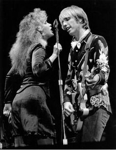 two people standing next to each other with microphones in their hands and one person holding a guitar