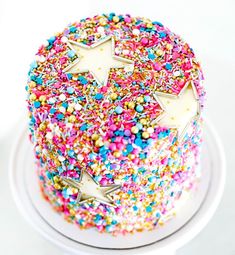 a colorful cake with sprinkles and stars on top is sitting on a white plate