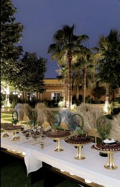 a table topped with lots of desserts next to palm trees