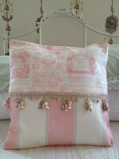 a pink and white pillow sitting on top of a bed