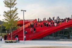 many people are walking up and down the red stairs in front of an office building