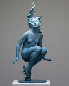 a blue statue sitting on top of a white pedestal next to a gray wall and floor