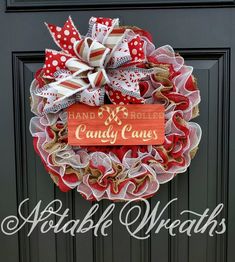 a red, white and tan wreath with a sign that says hand rolled candy canes on it