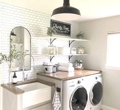 a washer and dryer in a room with white tiles on the walls, black accents