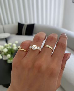 a woman's hand with two gold rings on it and one diamond ring in the middle