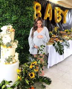 a pregnant woman standing in front of a cake