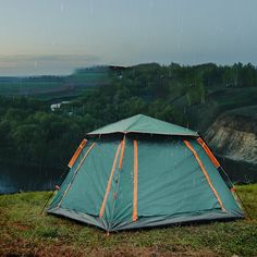 a tent pitched up on top of a lush green hillside